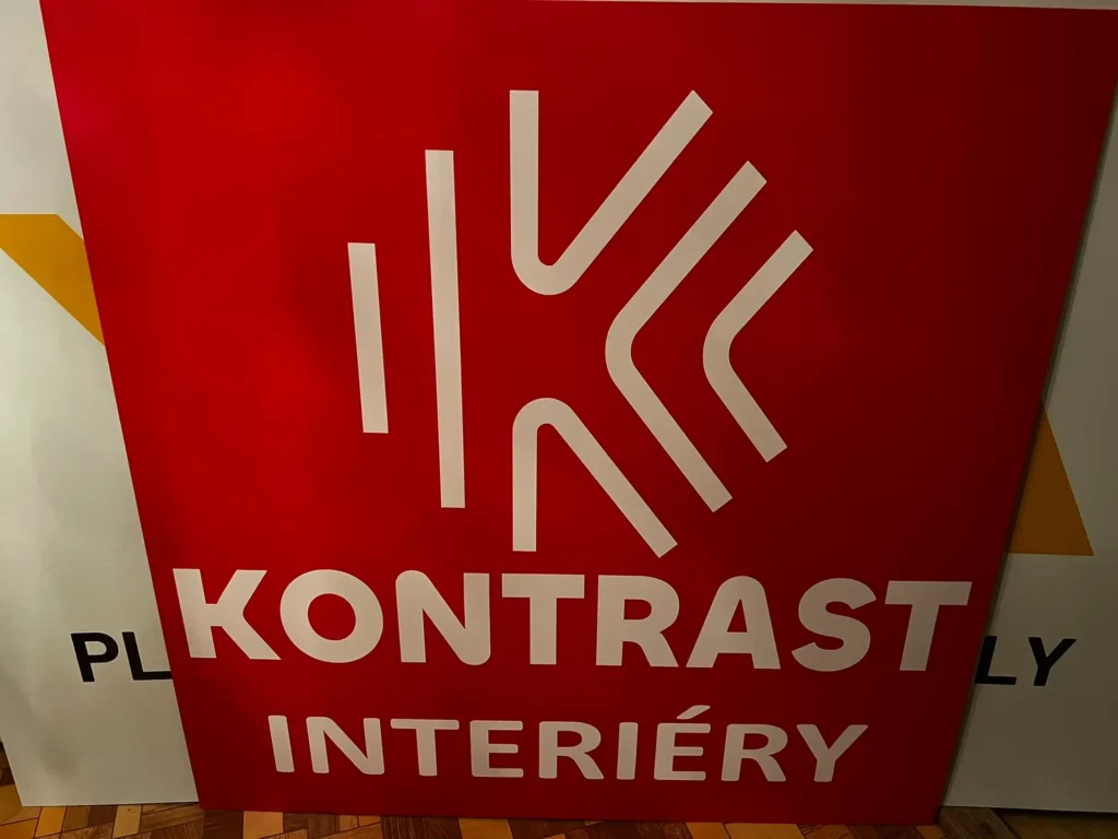 Informační reklamní poutač s červeným pozadím a bílým nápisem