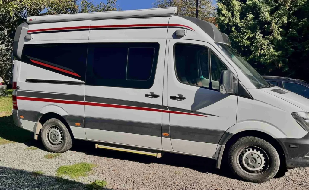 Bílá dodávka s červeno šedým polepem z boční strany